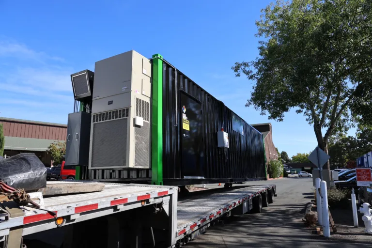 Large 8x40 black C1D1 extraction booth being loaded onto a flatbed truck outdoors