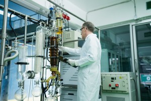 Older scientist preparing GMP outdoor booth for product extraction with protective gear