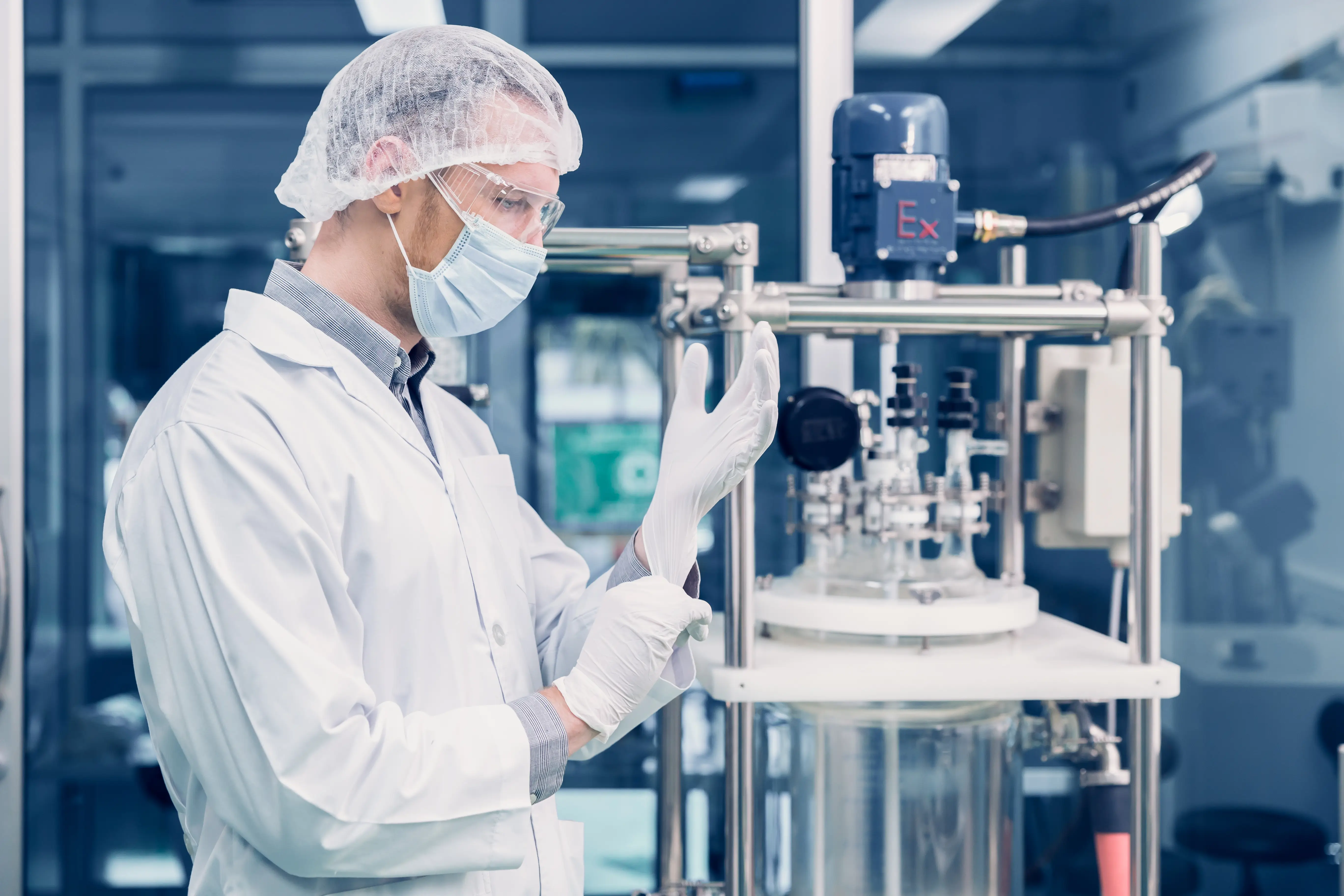 Male scientist in full protective lab gear working in a sterile, controlled laboratory environment